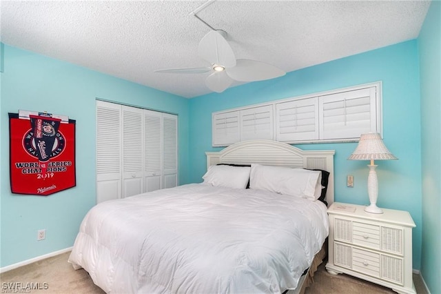 carpeted bedroom featuring ceiling fan, a closet, and a textured ceiling