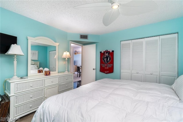 carpeted bedroom featuring ceiling fan, a closet, and a textured ceiling