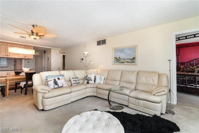 carpeted living room featuring ceiling fan and a textured ceiling