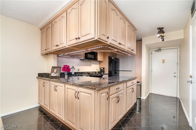 kitchen featuring dark stone counters, a textured ceiling, light brown cabinets, and black appliances