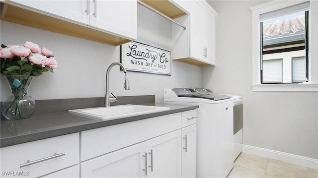 laundry room with washing machine and clothes dryer, sink, light tile patterned floors, and cabinets