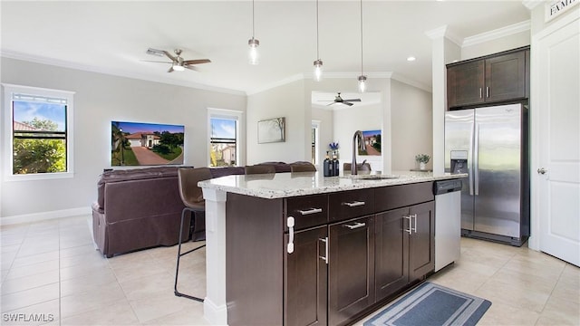 kitchen featuring appliances with stainless steel finishes, a kitchen breakfast bar, sink, pendant lighting, and a center island with sink