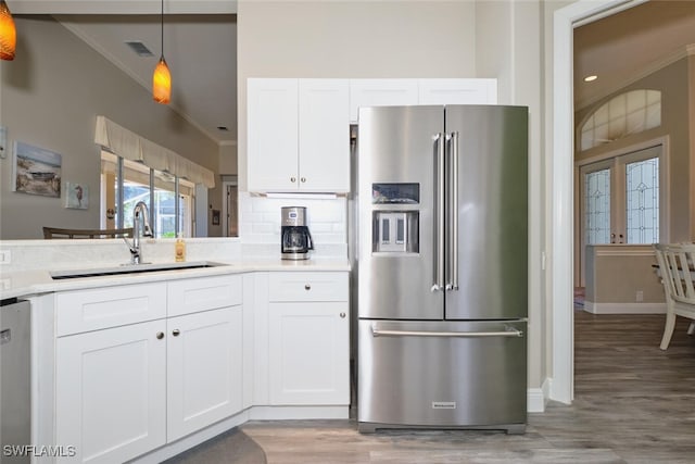 kitchen with pendant lighting, white cabinets, sink, light hardwood / wood-style floors, and stainless steel appliances