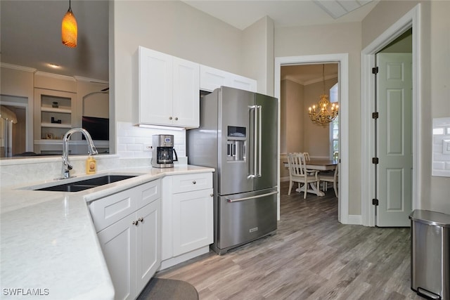 kitchen with white cabinets, hanging light fixtures, sink, light wood-type flooring, and high quality fridge