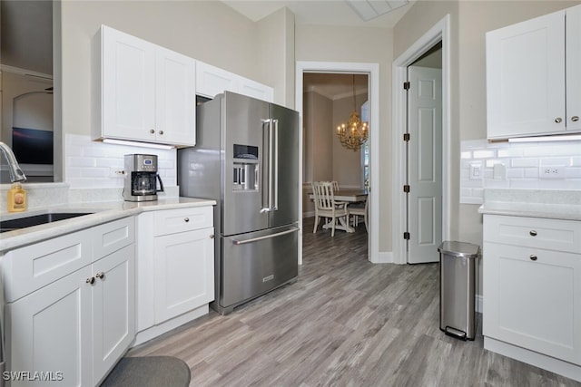 kitchen with backsplash, high quality fridge, white cabinetry, and crown molding