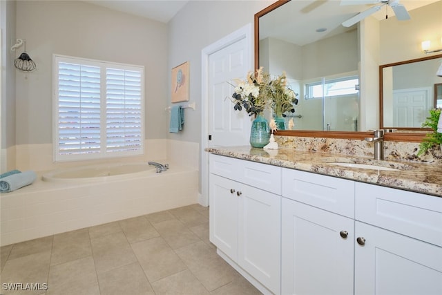 bathroom with tile patterned flooring, vanity, tiled tub, and a wealth of natural light