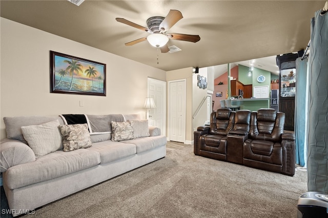 carpeted living room with ceiling fan and vaulted ceiling