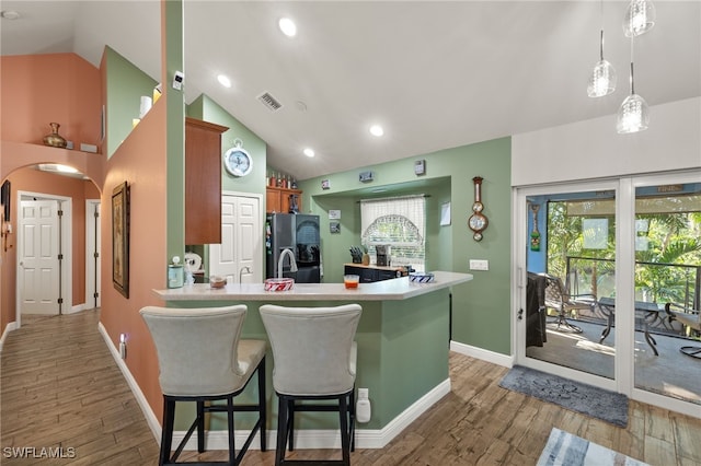 kitchen featuring pendant lighting, high vaulted ceiling, refrigerator, hardwood / wood-style flooring, and kitchen peninsula