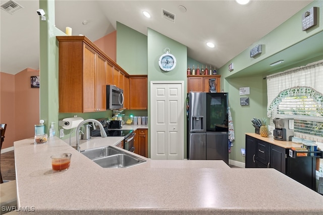 kitchen featuring sink, stainless steel appliances, kitchen peninsula, lofted ceiling, and hardwood / wood-style flooring