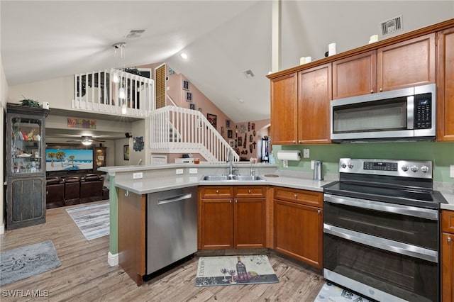 kitchen featuring sink, light wood-type flooring, decorative light fixtures, kitchen peninsula, and stainless steel appliances