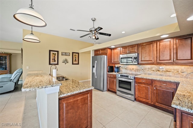 kitchen with light stone countertops, appliances with stainless steel finishes, tasteful backsplash, sink, and pendant lighting