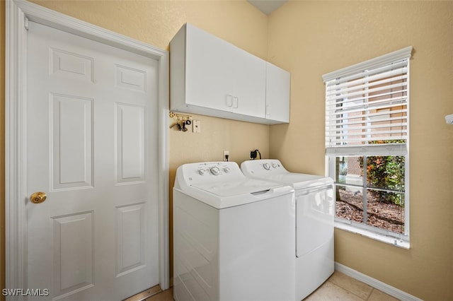 laundry area featuring washer and dryer, light tile patterned flooring, and cabinets