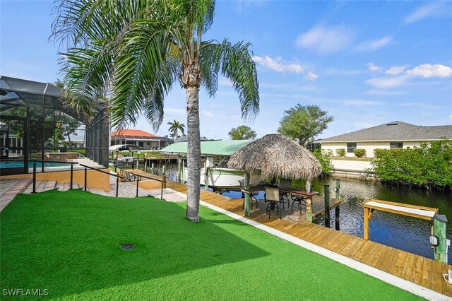 dock area with glass enclosure, a water view, and a yard