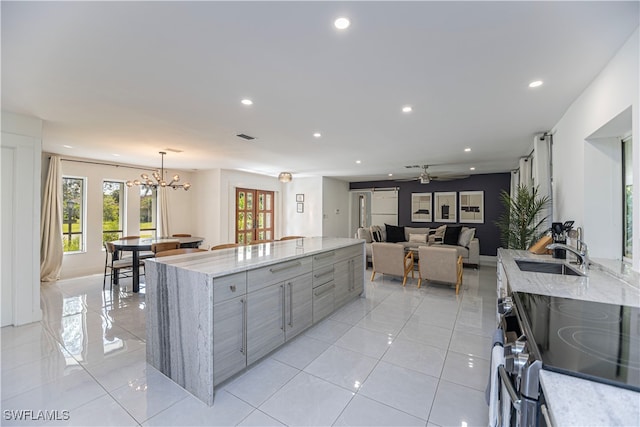 kitchen featuring stainless steel range with electric stovetop, pendant lighting, sink, a kitchen island, and light stone counters