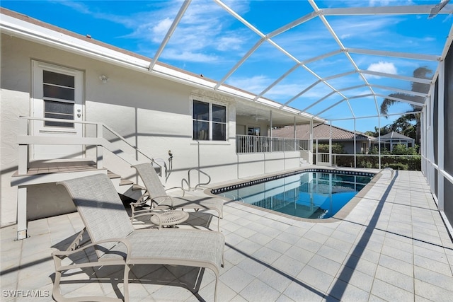 view of pool featuring glass enclosure and a patio