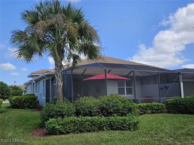 back of house with a lanai and a lawn