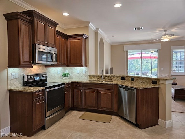 kitchen featuring kitchen peninsula, appliances with stainless steel finishes, light stone countertops, ornamental molding, and sink