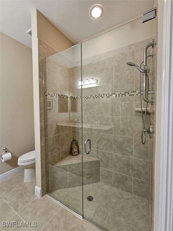 bathroom featuring tile patterned floors, toilet, and walk in shower