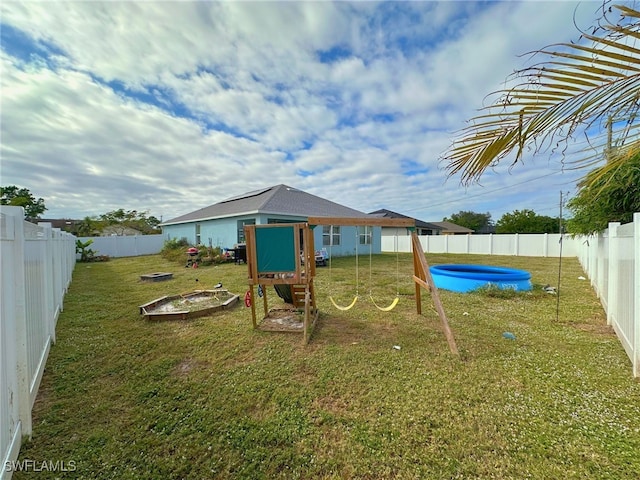 view of jungle gym featuring a swimming pool, a lawn, and an outdoor fire pit