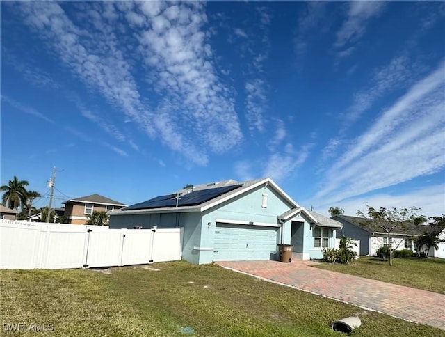 view of front of house featuring a garage, a front lawn, and solar panels