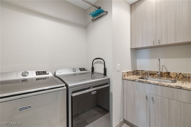 washroom featuring washing machine and clothes dryer, sink, and cabinets