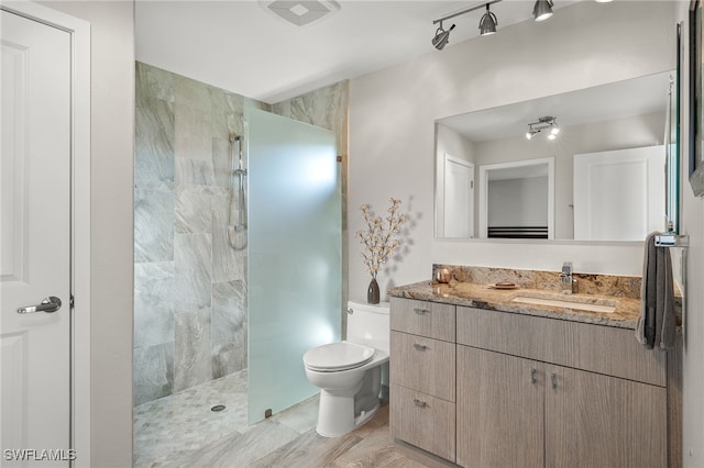 bathroom with vanity, toilet, and tiled shower