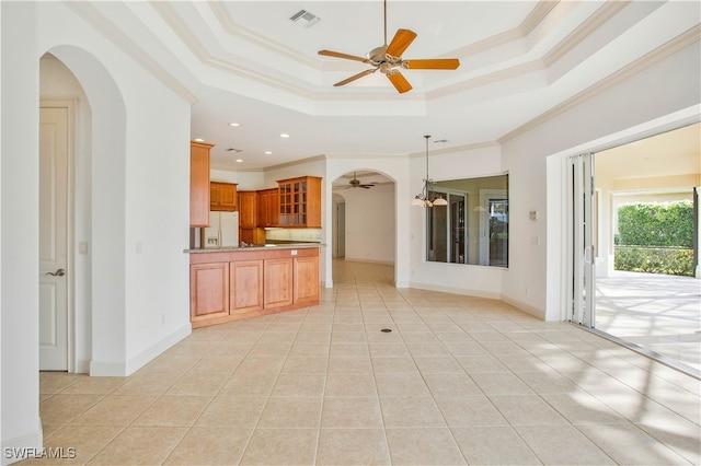 kitchen featuring white refrigerator with ice dispenser, light tile patterned floors, a tray ceiling, and crown molding