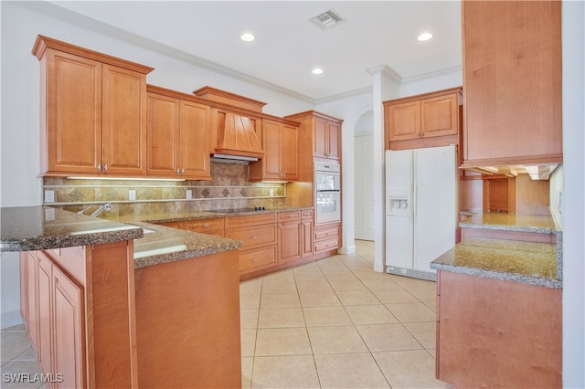 kitchen featuring kitchen peninsula, dark stone countertops, white appliances, light tile patterned flooring, and custom exhaust hood