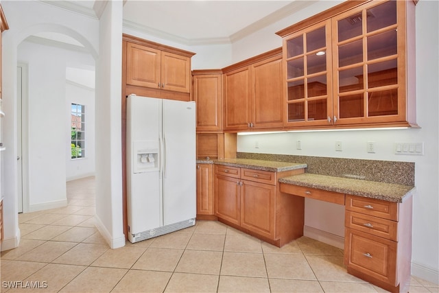 kitchen with white refrigerator with ice dispenser, built in desk, light stone counters, and ornamental molding