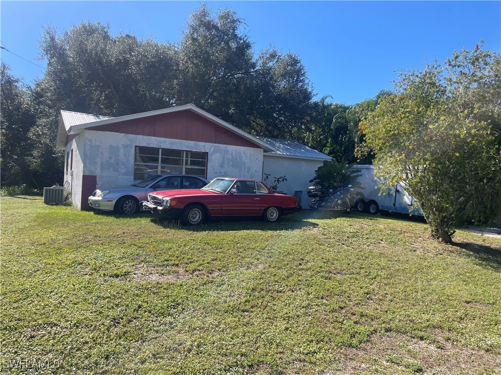 view of side of home featuring a yard and central AC unit