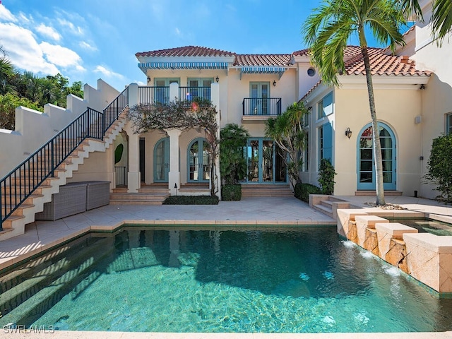 rear view of property featuring pool water feature, a balcony, a patio, and french doors