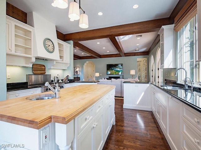 kitchen featuring a kitchen island, sink, dark hardwood / wood-style floors, white cabinetry, and butcher block counters