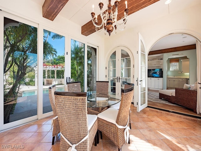 sunroom with french doors, a notable chandelier, and beam ceiling