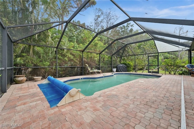 view of swimming pool featuring glass enclosure and a patio