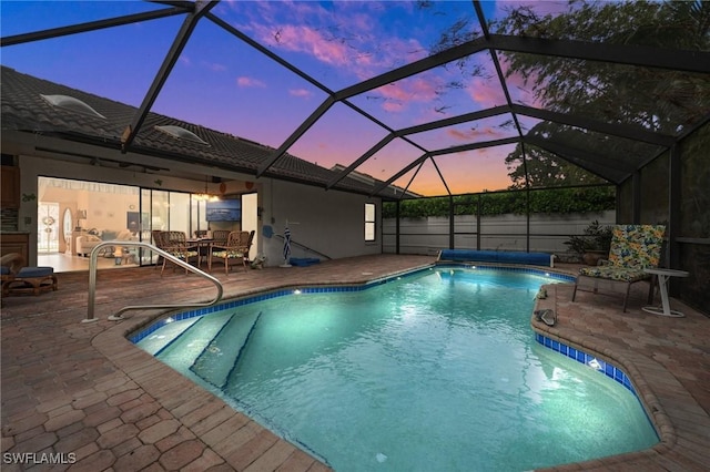 pool at dusk featuring a lanai and a patio