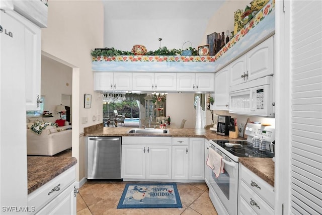 kitchen with white cabinets, light tile patterned flooring, white appliances, and sink