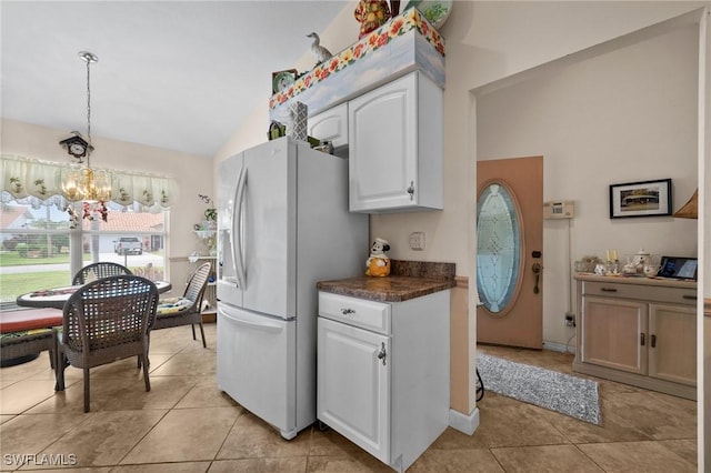 kitchen with white refrigerator with ice dispenser, decorative light fixtures, a notable chandelier, white cabinets, and lofted ceiling