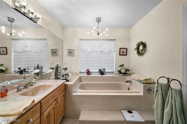 bathroom featuring tile patterned flooring, vanity, tiled bath, and a notable chandelier