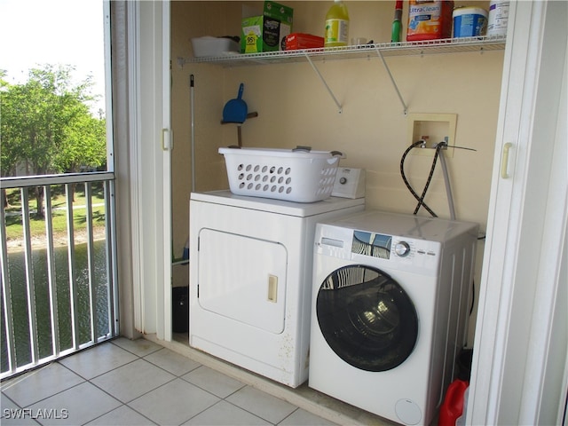 clothes washing area featuring washer and clothes dryer and light tile patterned floors