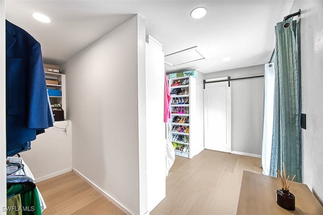 spacious closet featuring a barn door and light wood-type flooring