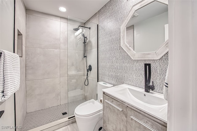 bathroom with tiled shower, vanity, and toilet