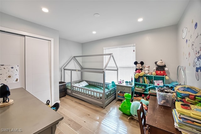 bedroom with light hardwood / wood-style floors and a closet