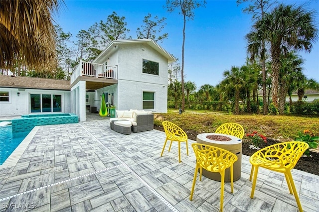 rear view of house featuring a balcony, an outdoor living space with a fire pit, and a patio area