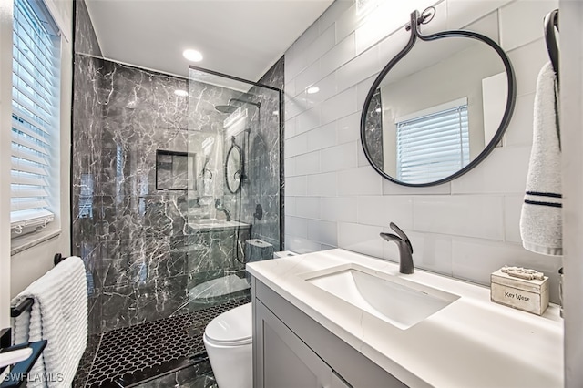 bathroom featuring vanity, tiled shower, tile walls, and toilet