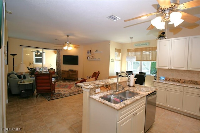 kitchen featuring dishwasher, a center island with sink, sink, light stone counters, and white cabinetry