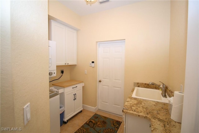 laundry room with cabinets, light tile patterned floors, electric dryer hookup, and sink