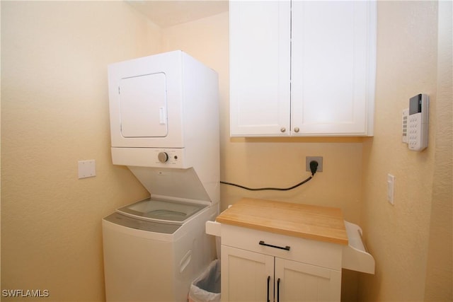 laundry area featuring stacked washer and dryer and cabinets