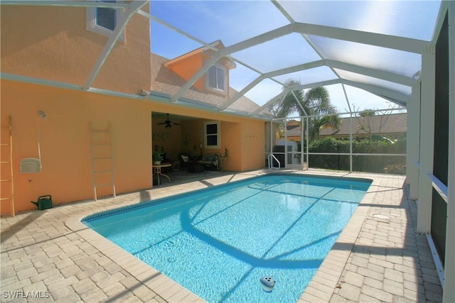 view of pool featuring glass enclosure, ceiling fan, and a patio