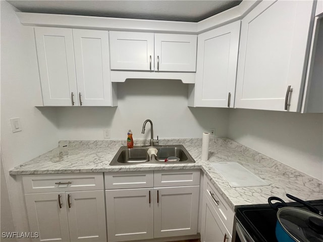 kitchen with white cabinets, range with electric cooktop, light stone countertops, and sink