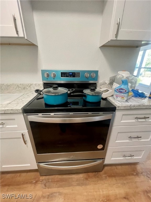 room details featuring white cabinets, light hardwood / wood-style floors, light stone counters, and electric stove